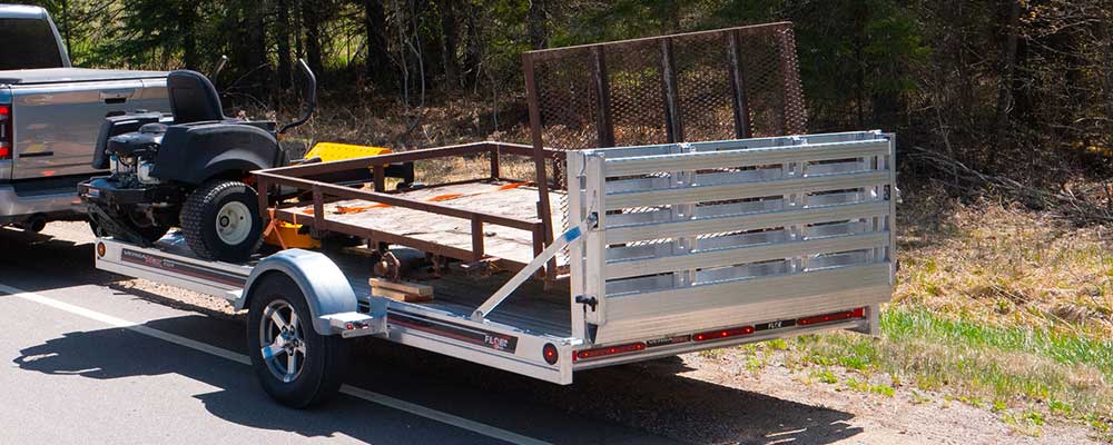 Aluminum vs steel utility trailer comparison showing lightweight aluminum trailer and heavy steel trailer